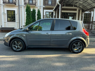 Sleek gray hatchback parked outside an elegant building under the warm afternoon sun