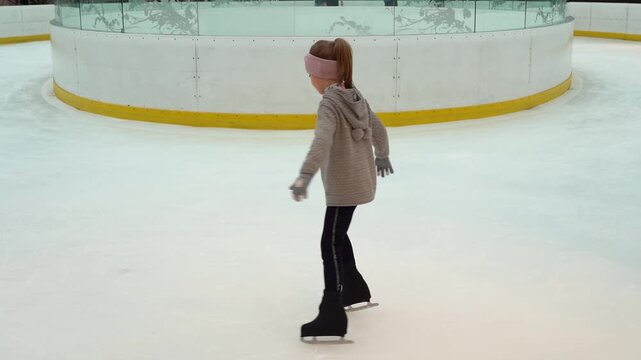 Little girl skates trains doing exercises spin on indoor ice rink. Child figure skating. Childrens sport