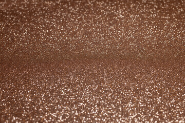 Glittering bronze texture with detailed middle area and soft blur on edges, offering radiant sparkling background with luminous metallic depth for design projects