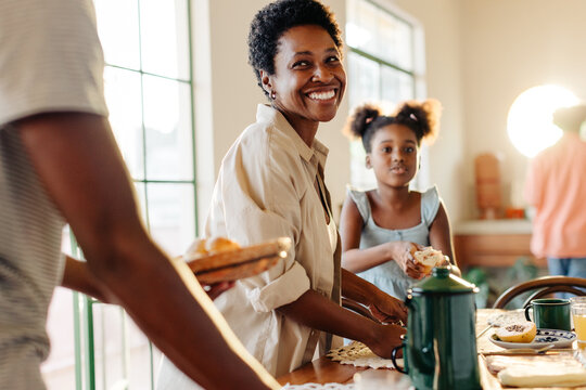 Mom and kids setting the table for a delicious Brazilian breakfast with pão de queijo - Powered by Adobe