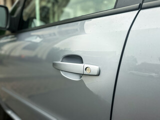 Close-up view of a silver car door handle showing intricate details and reflections in the...