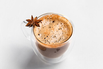 Glass cup of hot espresso with star anise on white background