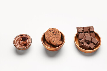 Bowls with cookies, chocolate and cream on white background