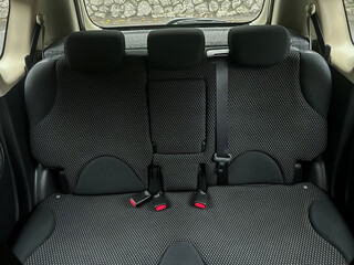 Back seat of a compact car shows neat fabric upholstery and ready seat belts, capturing a moment of quiet anticipation on a day trip