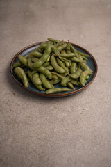 asian edamame beens toped up on a blue plate