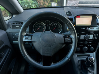 Modern car interior showcasing a sleek dashboard and sophisticated controls set against lush greenery outside