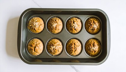 Top-down view of eight freshly baked golden brown muffins with a crumb topping in a dark metal baking pan.