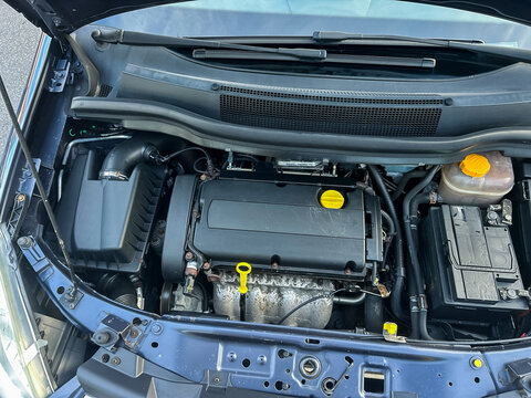 Under the hood of a compact car showing the inner workings of the engine during a bright daylight inspection on a road trip