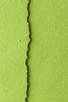 Textured green matcha powder split by narrow seam at center on vertical frame, versatile background for food branding and packaging.