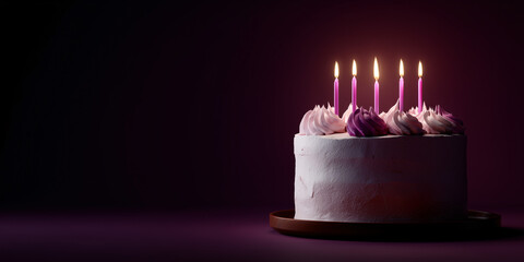 A birthday cake with lit candles set against a dark background, evoking a sense of celebration and anticipation