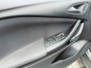 Elegant car interior showcasing a sleek door panel with modern controls and textures on a sunny day near the city street