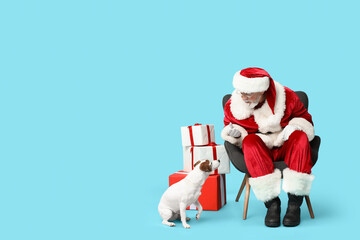 Santa Claus with cute Jack Russell Terrier dog and Christmas gift boxes on blue background