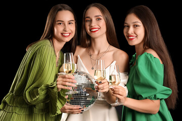 Beautiful young women with champagne and disco ball on dark background. New Year celebration