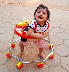 Fototapeta premium Little girl enjoying the baby walker for the first time starring at the sky with a joyous smile. 