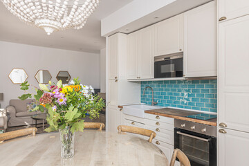 Dining set with a round birch table and Nordic chairs, with a bouquet of heather and dried flowers in earth tones