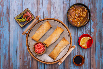 Composition of transparent shrimp spring rolls revealing the filling, served on a glass plate with purple lettuce and aromatic herbs