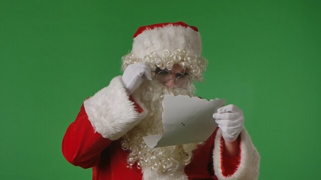 Santa Claus reading a letter on a green chroma key background. Ideal for Christmas themed compositions.