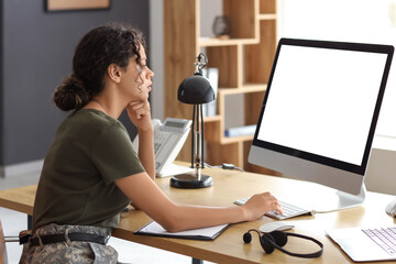Female African-American soldier working with computer at table in headquarters