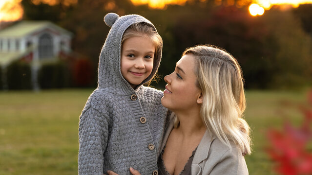 Mother and little daughter walk in autumn park at sunset. Happy family in nature outdoors. Weekend leisure with child - Powered by Adobe