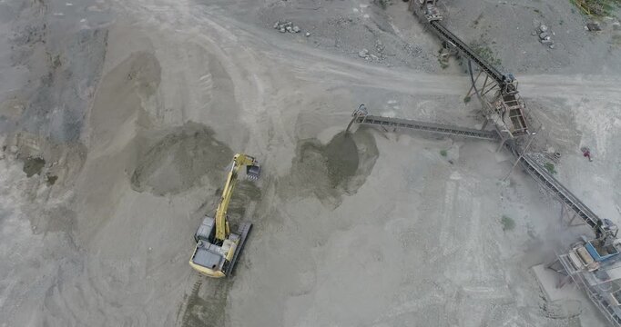 Aerial view of heavy machinery and conveyor belts with contrasting textures, tones, and colors in a quarry, Palu, Central Sulawesi, Indonesia.