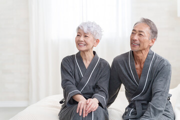 寝室にいるバスローブを着たシニア夫婦