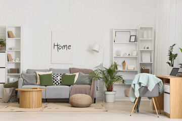Interior of living room with sofa, shelf units and workplace