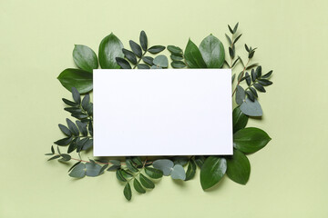 Blank card with different fresh green leaves on color background