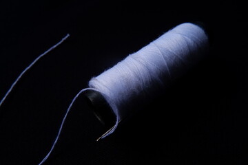 White Thread and Needle on Dark Surface – Sewing Essentials in Dramatic Closeup
