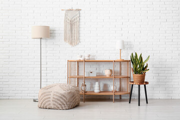 Wooden shelving unit with lamps and soft pouf in modern room