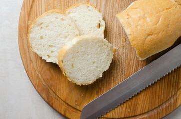 The process of cooking French onion soup. Baguette cut into slices on a wooden cutting board. Traditional cuisine concept. Horizontal orientation. Selective focus.