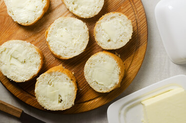 The process of cooking French onion soup. Baguette cut into slices with butter on a wooden cutting board. Traditional cuisine concept. Horizontal orientation. Selective focus.