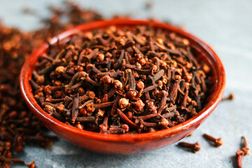Cloves in a bowl on a gray background. Spices.