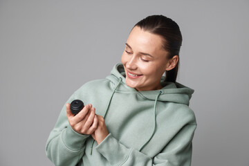 Young woman with hidden spy camera on light grey background