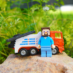 Obraz premium Minecraft Steve figure with toy tow truck on a rock outdoors