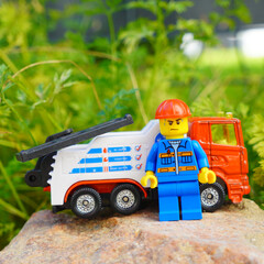 Obraz premium Lego mechanic figure stands next to a tow truck on a rock outdoors