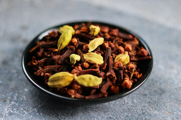 Spices and herbs: cardamom and clove in a black bowl