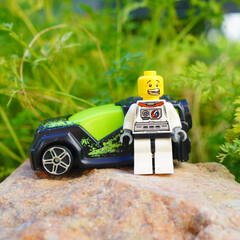 Obraz premium Lego astronaut figure standing next to a toy car on a rock