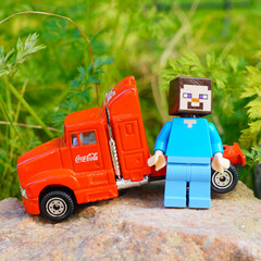 Naklejka premium Minecraft Steve figure with a red Coca-Cola truck on a rock outdoors
