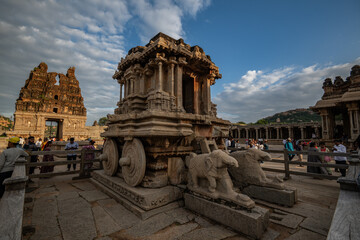 Hampi, India - 01 November 2025: View of the stone chariot, a jewel of ancient craftsmanship, stands majestic against a backdrop of temple ruins and a vast sky.