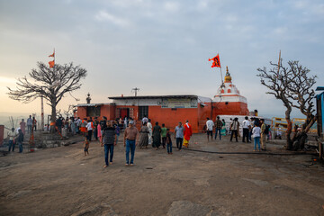 Hampi, India - 02 November 2025: View of the vibrant Hanuman Temple atop Anjanadri Hill, where devotees gather under a vast sky, the temple's orange hues contrasting against the muted landscape.