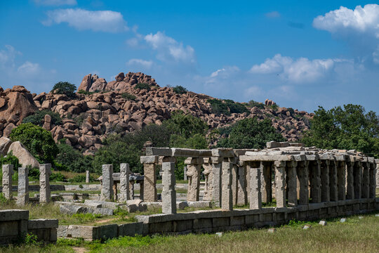 Hampi, India - 01 November 2025: View of the weathered stone ruins standing in silent contrast against the rugged, boulder-strewn landscape and clear blue sky.