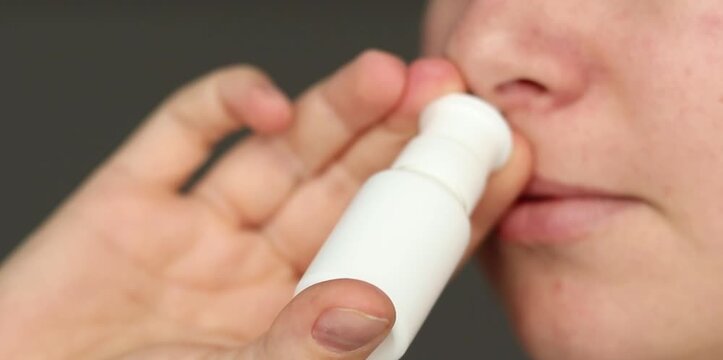Close up of a female using nasal spray, relieving blocked and runny nose 