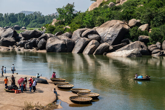 Hampi, India - 01 November 2025: View of the Tungabhadra River flowing gently past rugged, rocky shores where coracles rest, reflecting the lush greens and earthy tones.