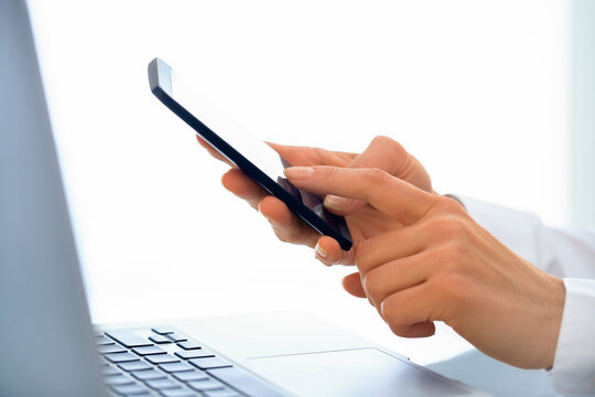 Businesswoman typing message on mobile phone in office.
