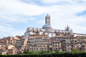 Fototapeta premium Majestic Siena cathedral in Tuscany rises above ancient buildings in a charming Italian town, showcasing stunning architecture and inviting travellers to explore its rich history and vibrant culture