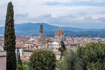 Obraz premium Scenic view of Florence historical cityscape featuring stone buildings, lush greenery, and iconic dome under cloudy sky, inviting exploration of rich culture and history
