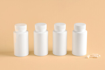Blank plastic vitamin bottles and pills on beige background