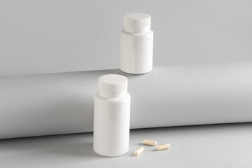 Blank plastic vitamin bottles and pills on grey background
