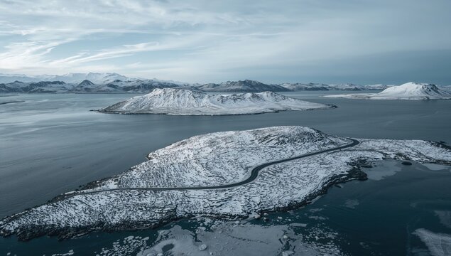 Aerial view of a road winding through snowy islands on a water body, highlighting seasonal change
