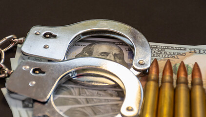 Obraz premium Metal handcuffs and rifle bullets with dollar banknotes symbolizing crime power and corruption